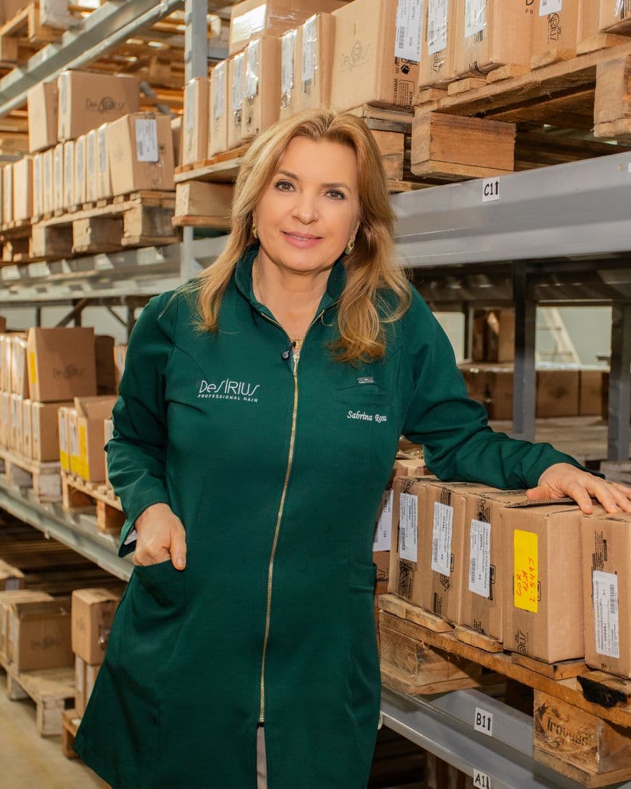 Sabrina Rosa no estoque da fábrica, entre prateleiras de caixas De Sírius